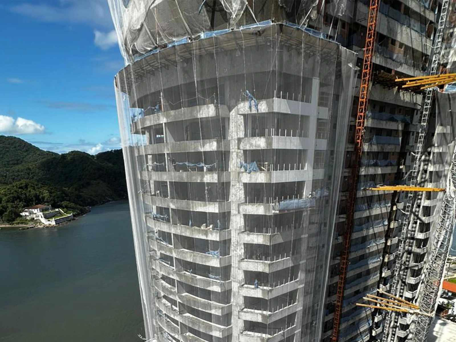 Edifício de alto padrão em construção com sistema completo de telas de fachada R2K para contenção de detritos e segurança em altura.
