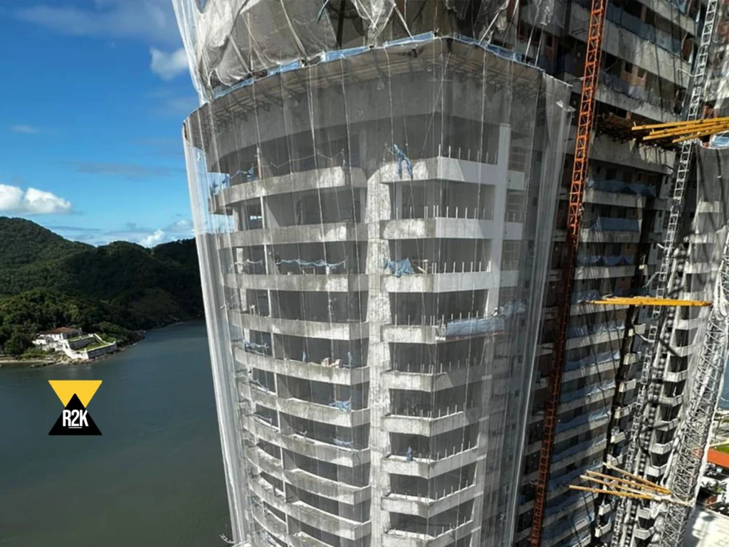 Edifício de alto padrão em construção com sistema completo de telas de fachada R2K para contenção de detritos e segurança em altura.