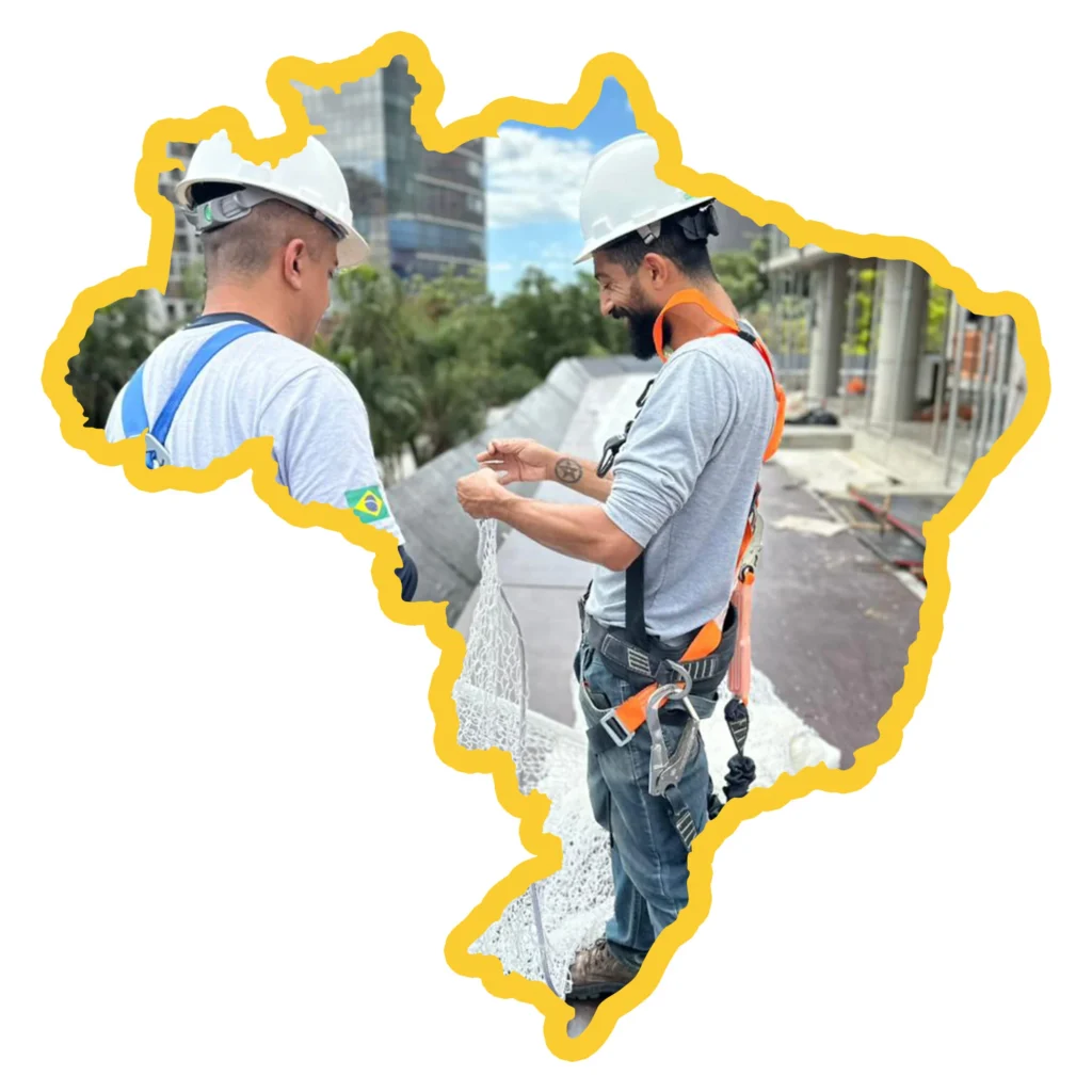 Instaladores da R2K Proteção Coletiva trabalhando em altura dentro de um contorno do mapa do Brasil, simbolizando o atendimento nacional e expertise em engenharia de segurança.