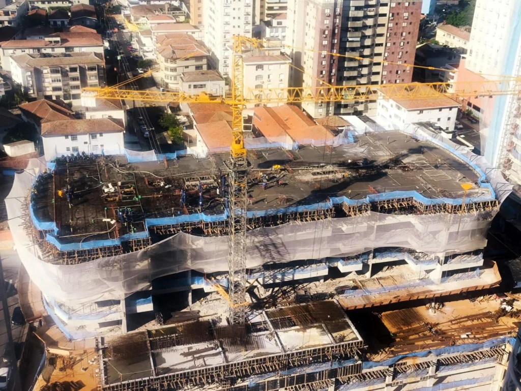 Vista aérea de canteiro de obras utilizando Sistema Limitador de Quedas de Altura (SLQA) instalado pela R2K, garantindo proteção periférica total.
