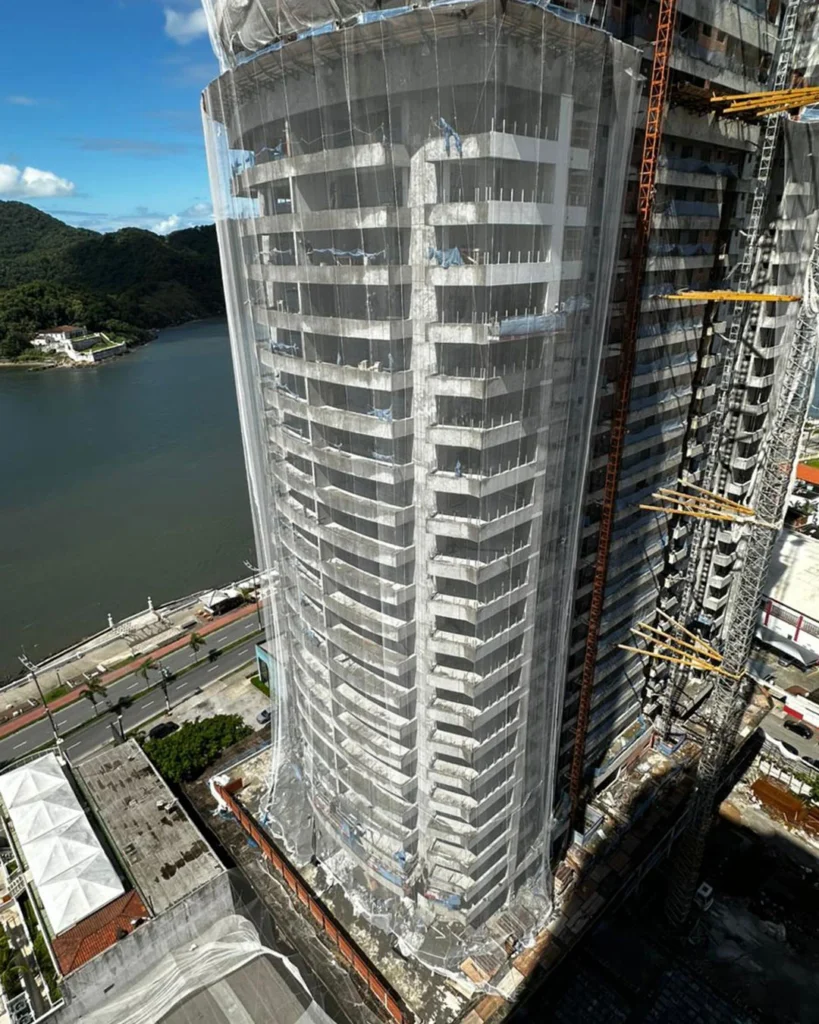 Edifício de alto padrão em construção com sistema completo de telas de fachada R2K para contenção de detritos e segurança em altura.